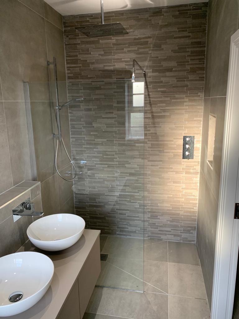 A walk-in shower with a striped stone feature wall and two basins