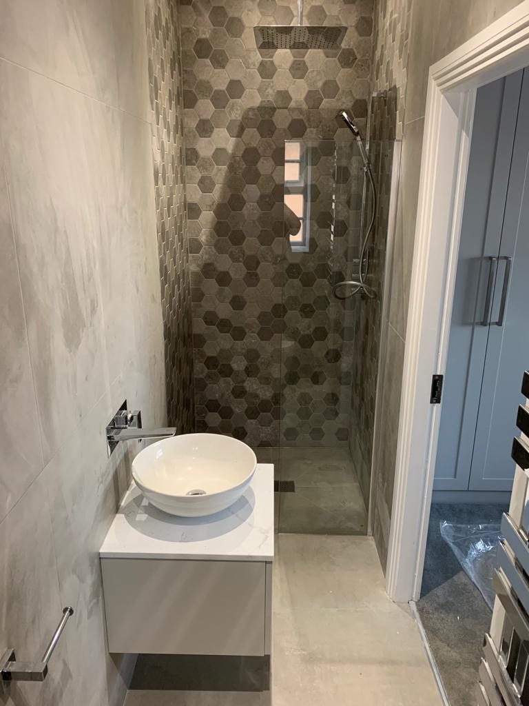 A hexagon-tiled shower with a wall-hung basin