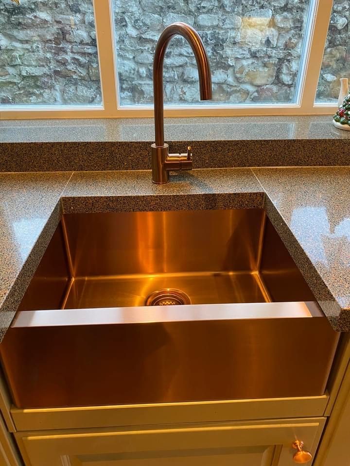 A copper kitchen sink with a matching copper mixer tap